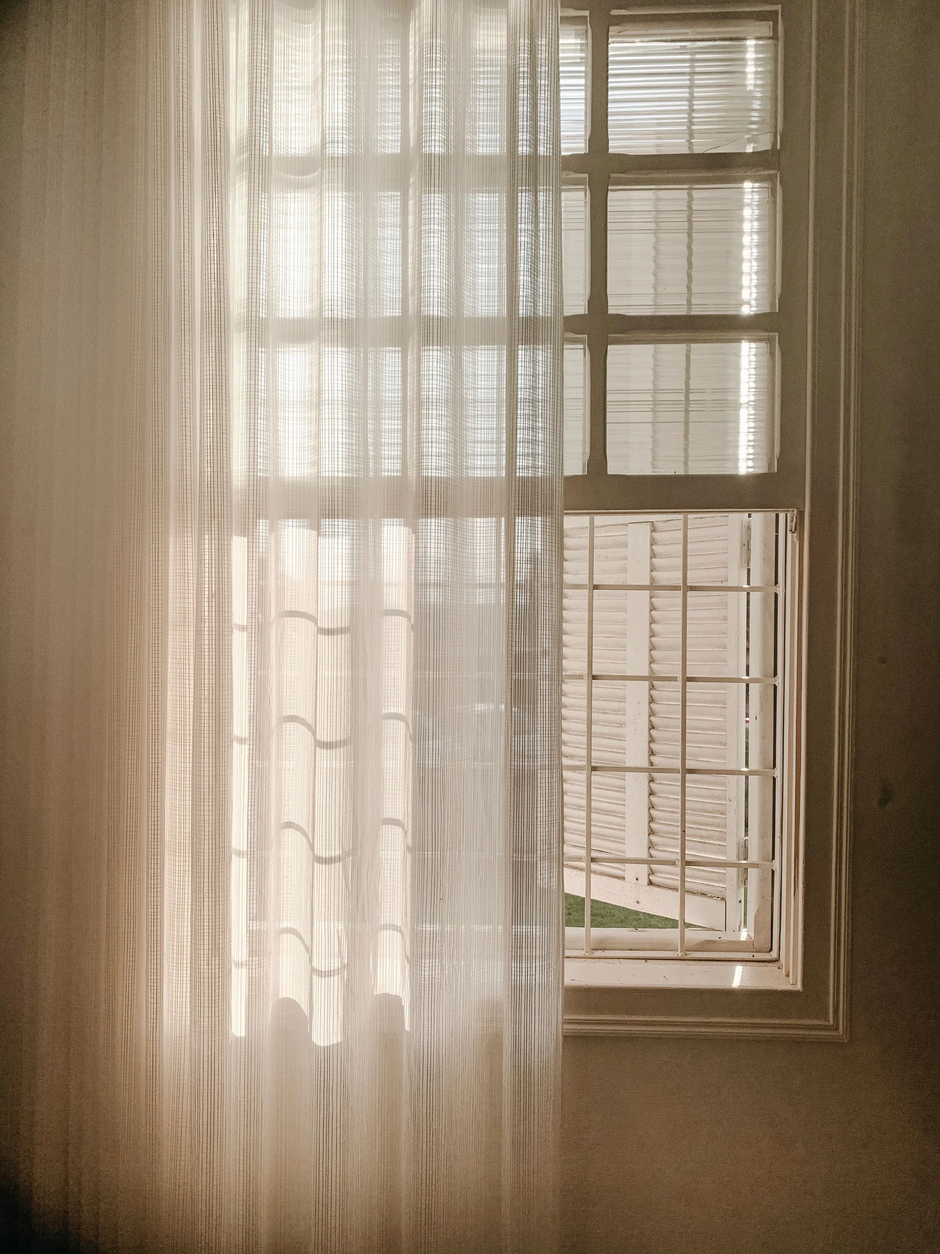 Sheer white curtains moving softly beside an open window